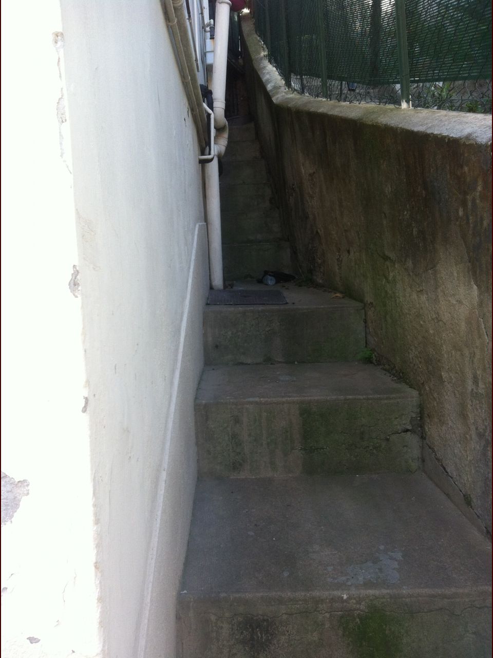 Le mur de la cuisine avec une bouche d'gout contre le mur. En montant les escaliers sur la gauche on trouve la court du voisin (autre photo).
