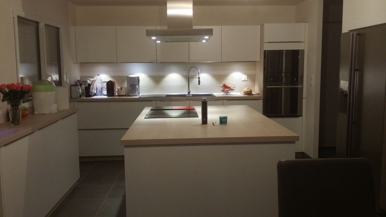 C'est une cuisine en blanc strié avec un plan de travail imitation bois clair.