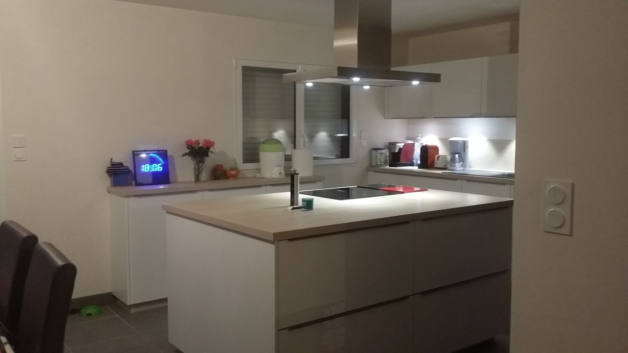 C'est une cuisine en blanc strié avec un plan de travail imitation bois clair.