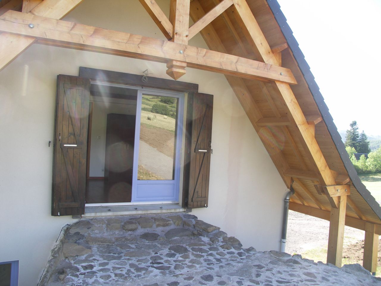 L'auvent OUEST et sa terrasse empierrée qui donne un accès direct au niveau 1, (autrefois, dans les burons traditionnels, on accédait au fenil par ce moyen, les bonnes solutions sont à reprendre !)