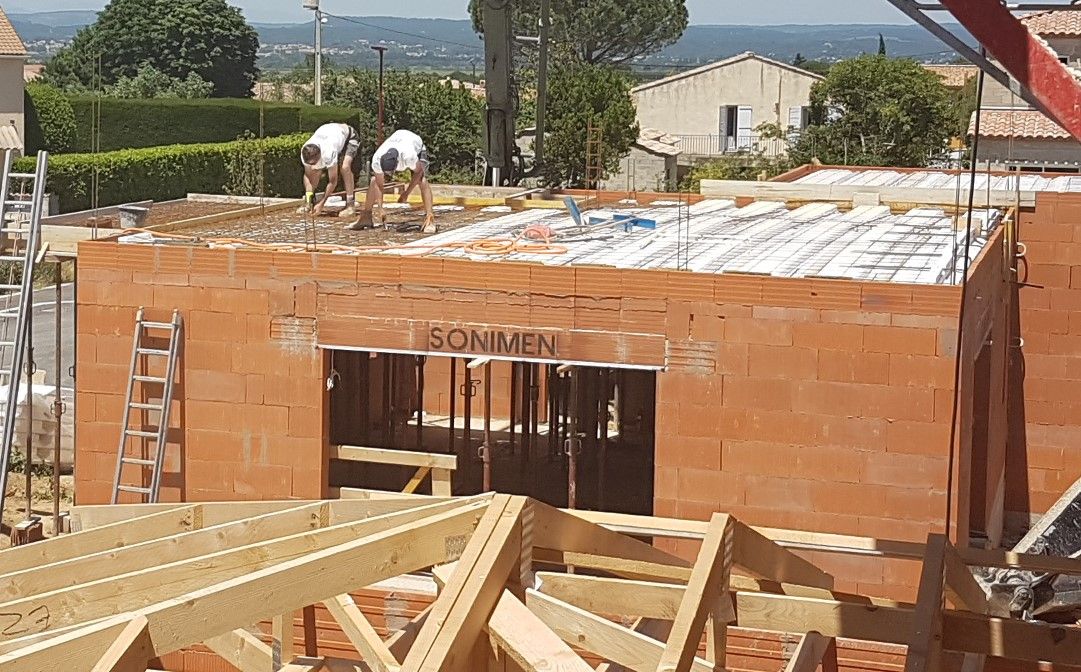 les maçons finissent d'attacher la ferraille avant de couler le plancher de l'étage