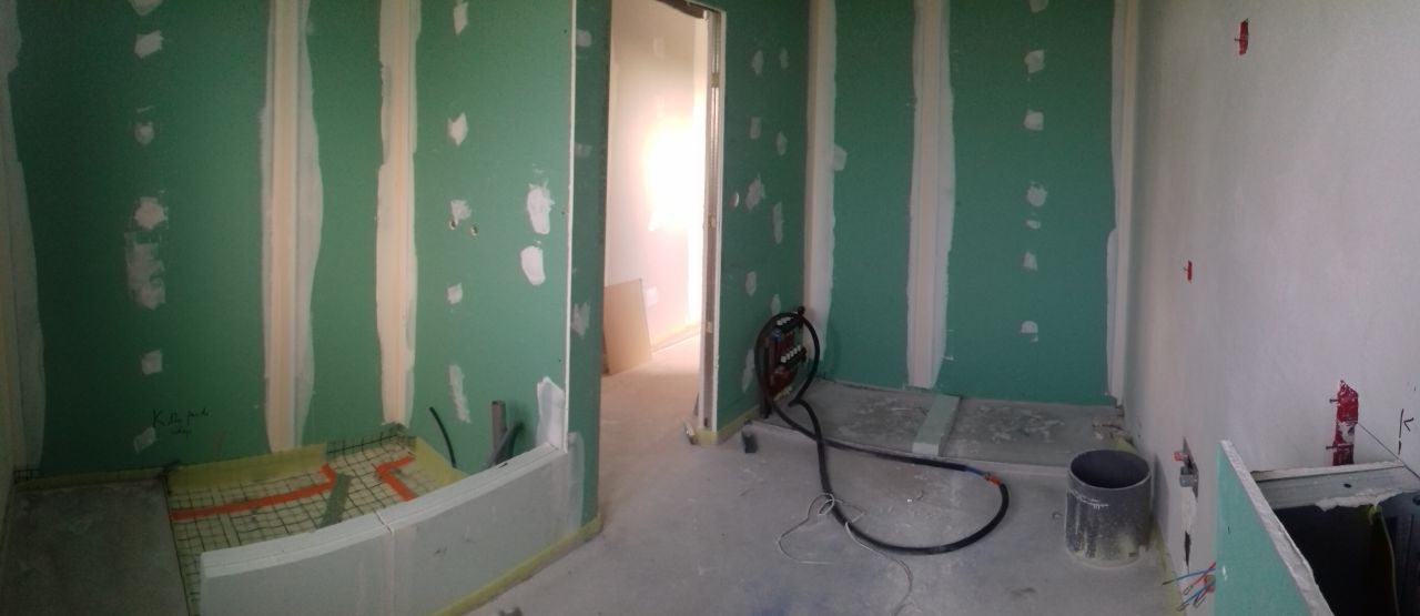 Vue panoramique de la salle de bain de l'étage (de gauche à droite : WC suspendu, meuble, trappe à linge, baignoire au fond, porte et espace douche).