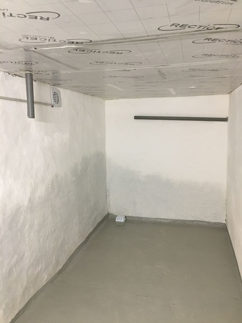 Un morceau du sous-sol termin : enduit + chaulage, isolation de la dalle, peinture au sol, extracteur, tuyaux d'vacuation de la salle de bain au-dessus en attente