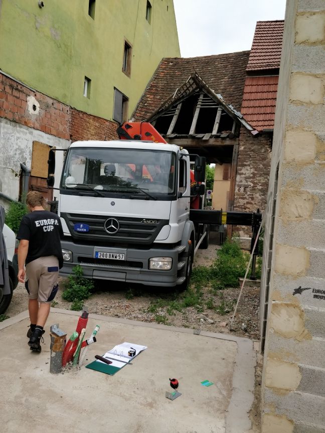 Configuration du terrain pour le montage : le petit camion grue de Heim va chercher quelques panneaux sur le camion et les ramne en passant (tout juste) sous le porche pour les dcharger