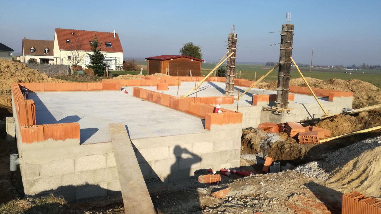 Montage du premier rang de briques pendant le schage de la chape et coulage des poteaux