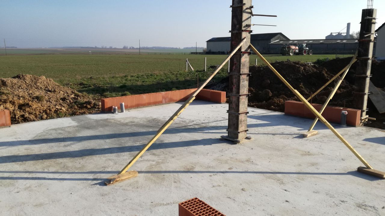 Montage du premier rang de briques pendant le schage de la chape et coulage des poteaux