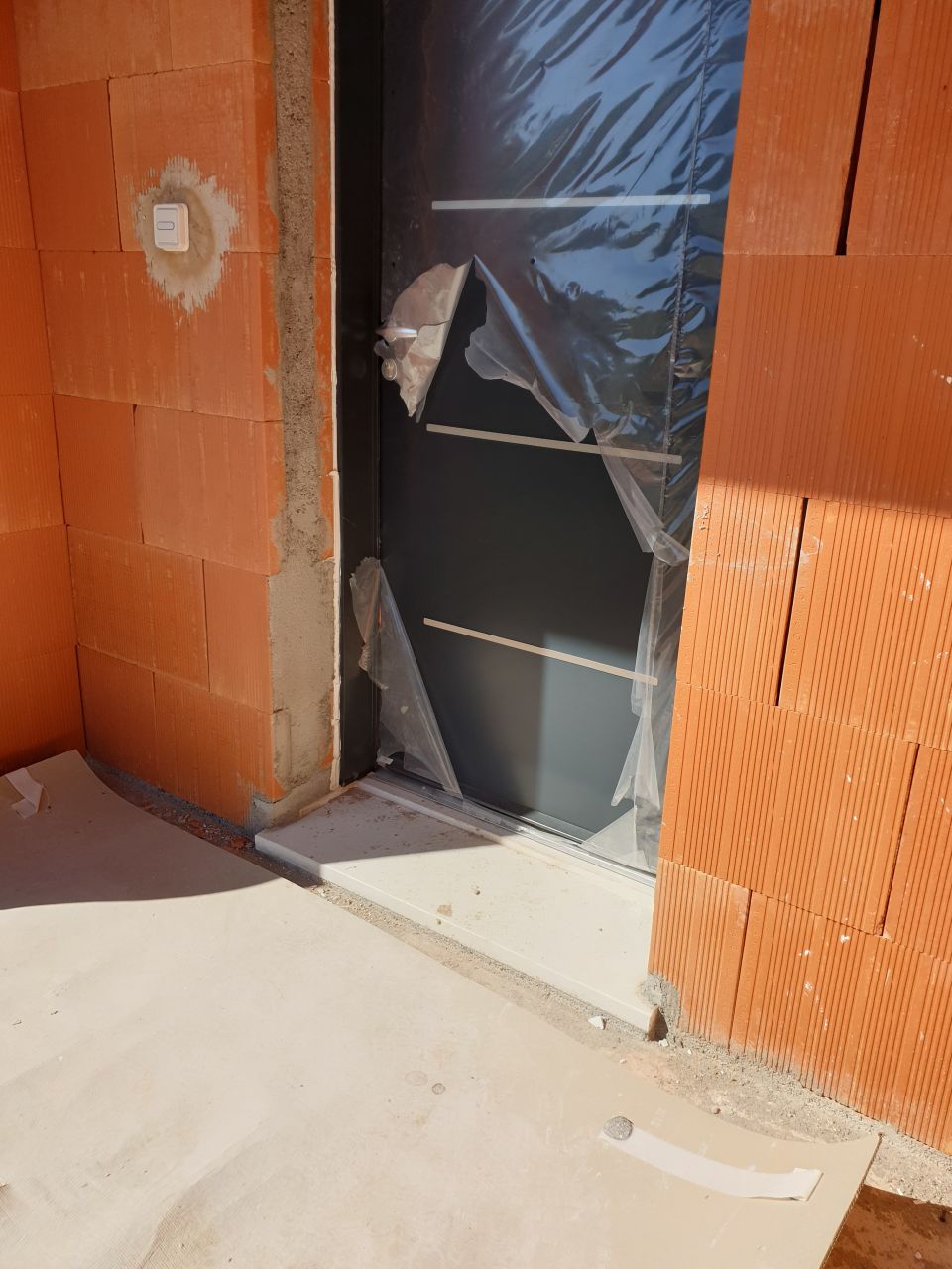 Porte d'entrée initialement protégée avec une plaque de PVC + un film plastique... Il ne reste presque plus rien