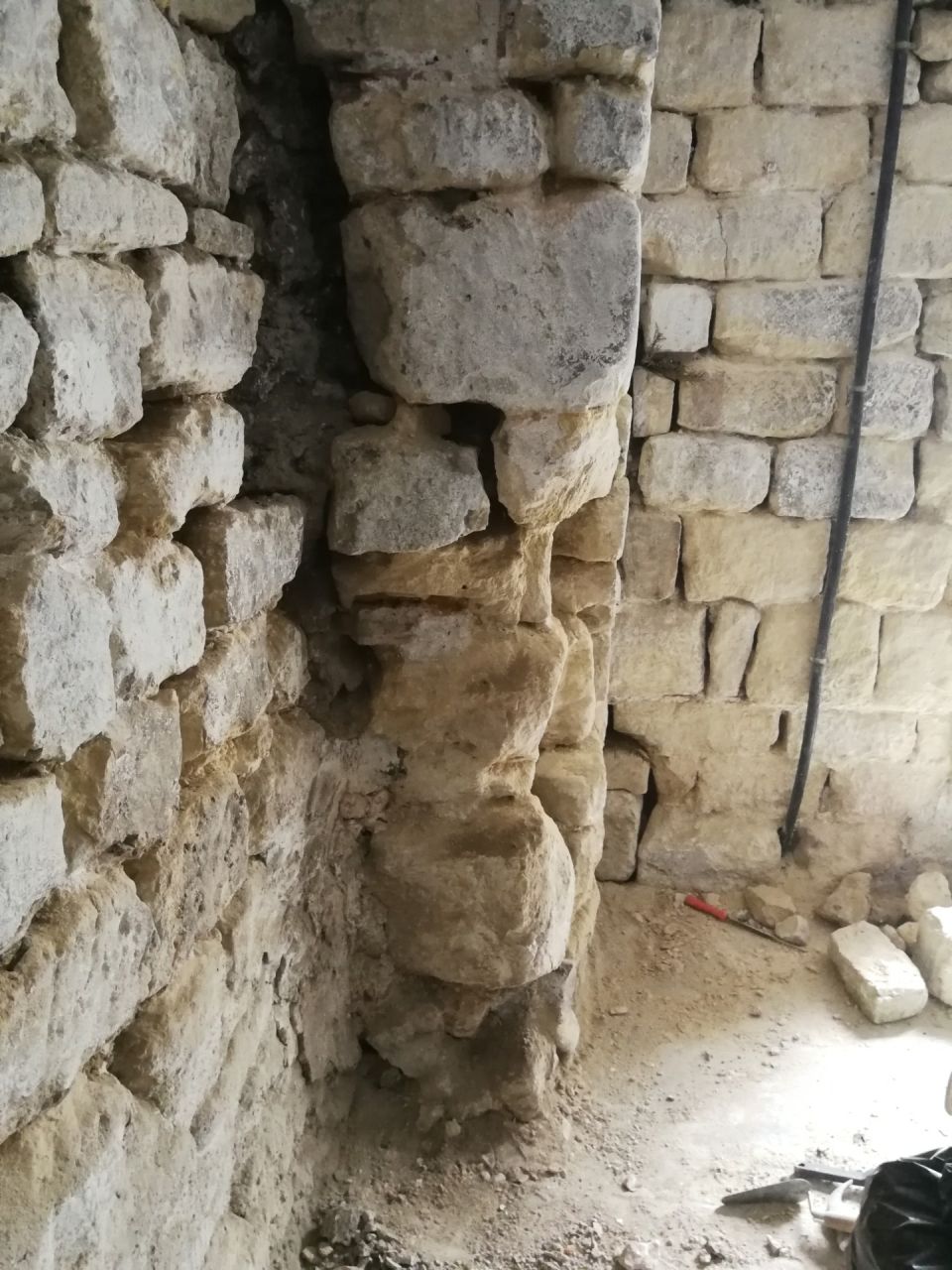Vue profil d'un poteau mis  nu de ciment avec pierres trs uses