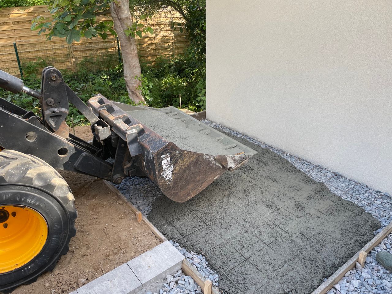 Jérémie dépose le ciment qui va constituer une mini dalle pour un abri de jardin arrière