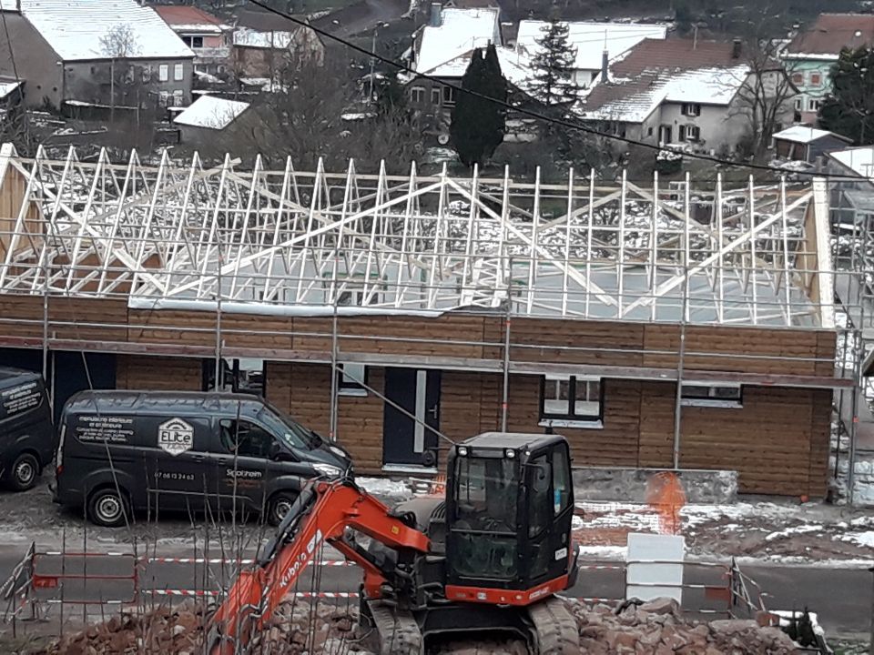 Poursuite de la charpente et bardage de finition aux jonctions des murs.