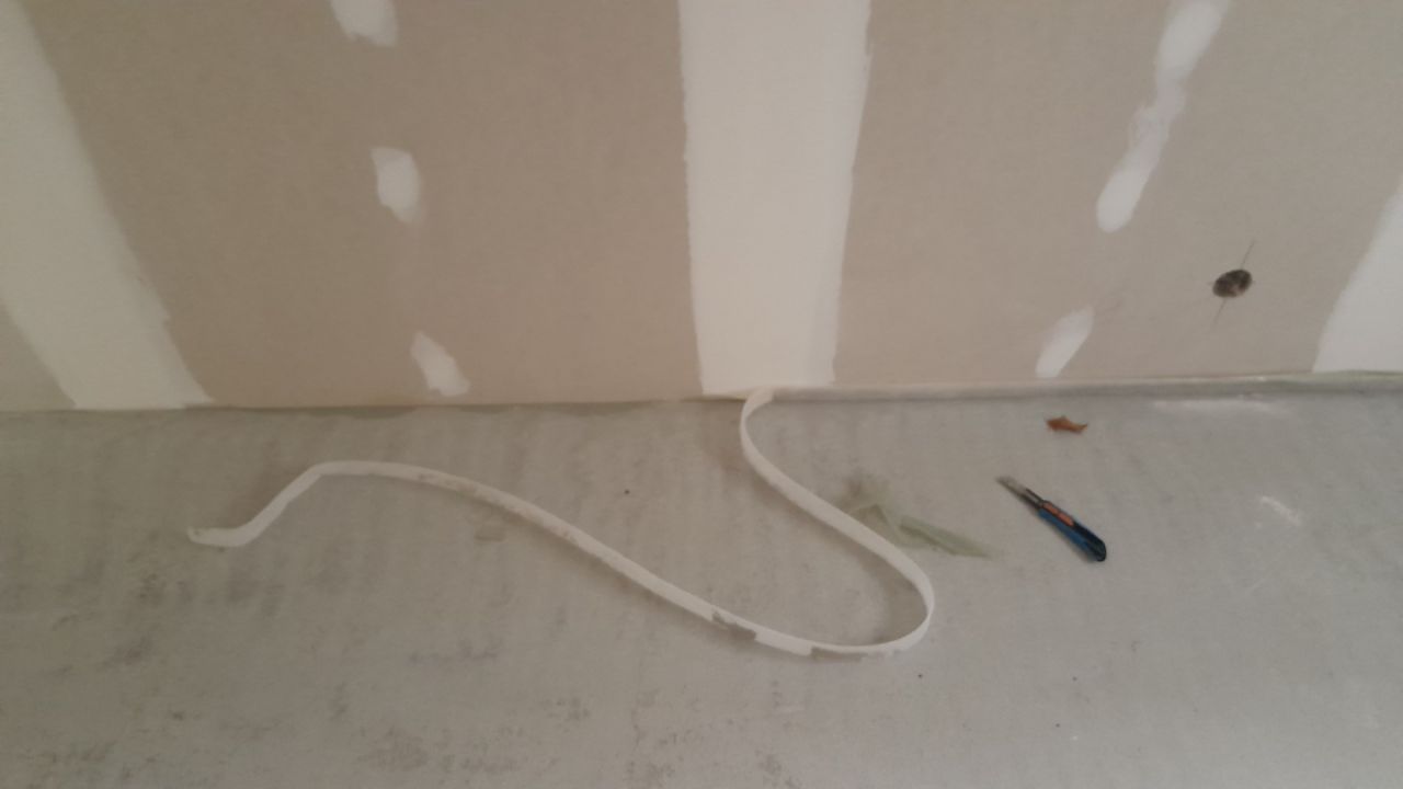 Découpe du surplus des joints de dilatation de la chape ciment.