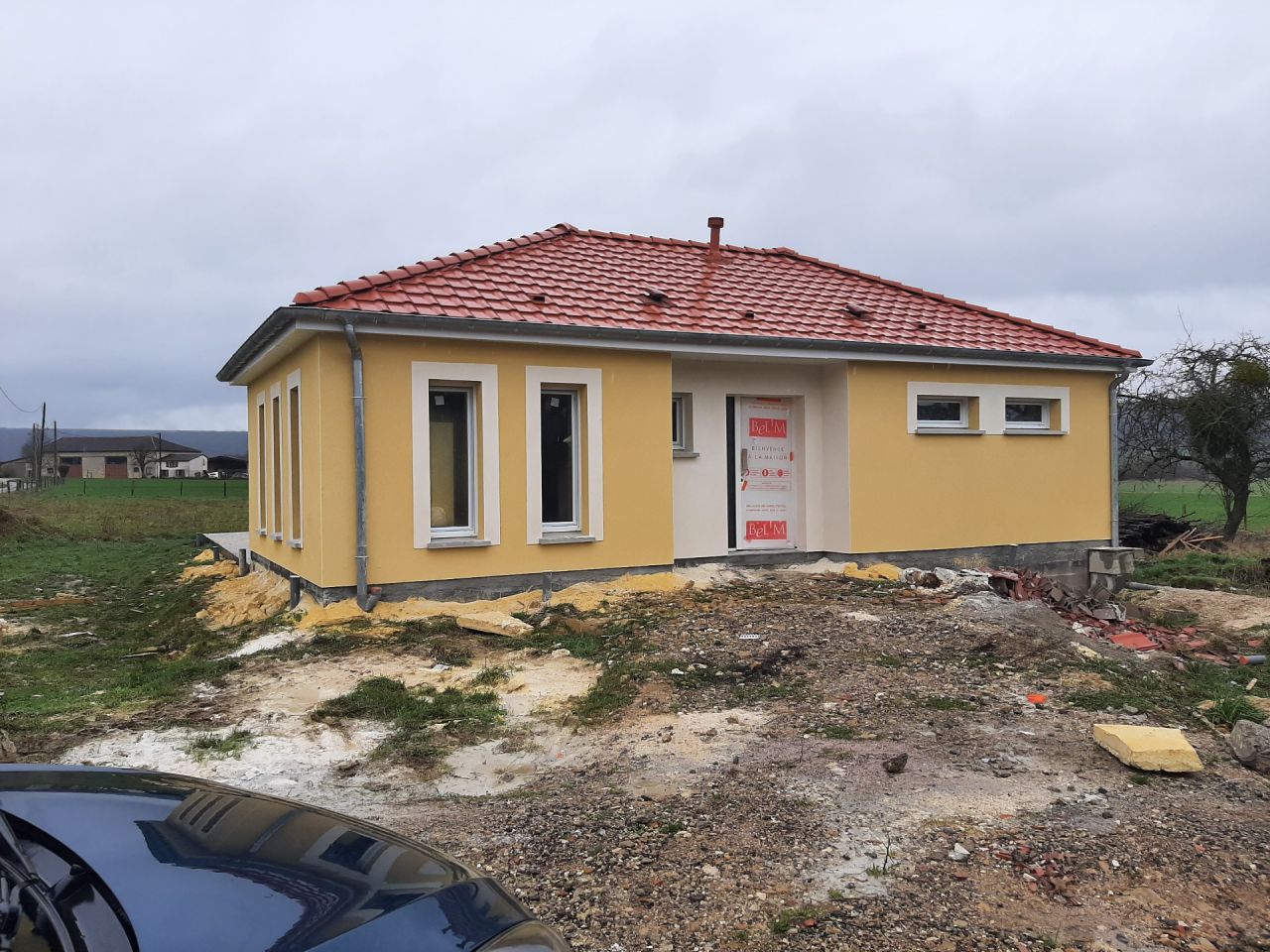 Couleur jaune Dune pour les murs et jaune Orpiment pour les contours des fenêtres et l'entrée. Façade avant.