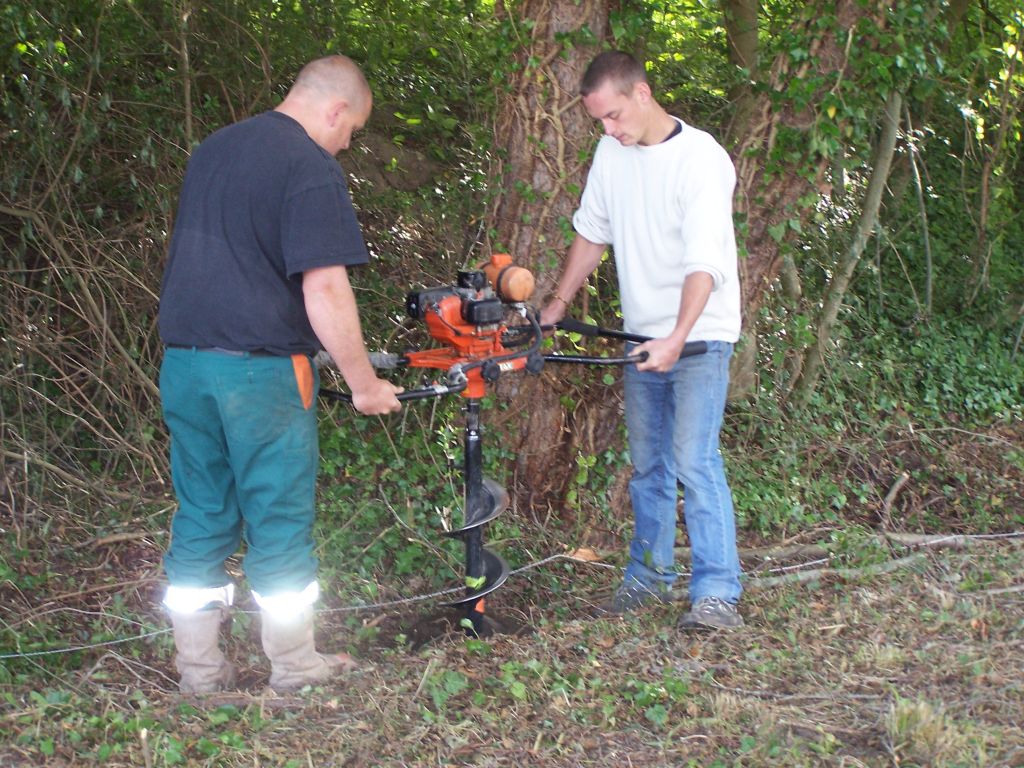 On creuse les trous  la tarrire pour y planter les piquets de cloture.