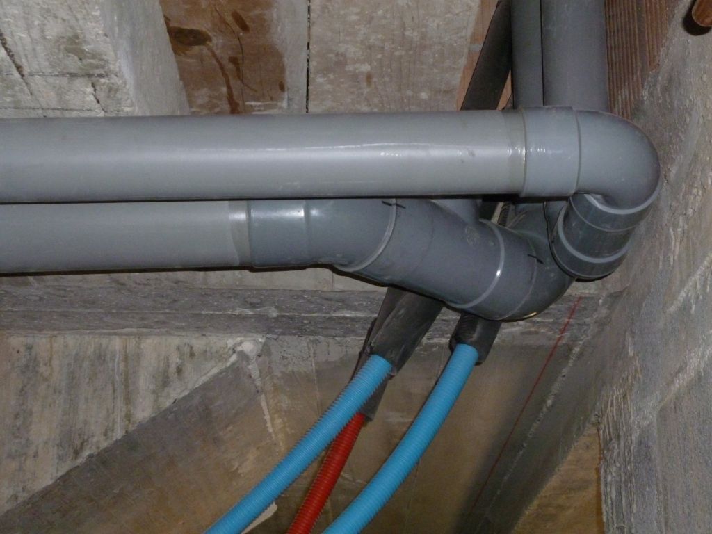 Plomberie - évacuations et tuyaux en cours de pose à la cave