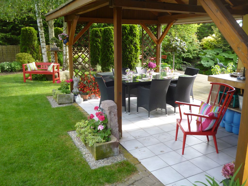 Table mise pour une soirée BBQ avec banc et chaise rouges habillés de coussins multicolores. Bon appétit !!!!!