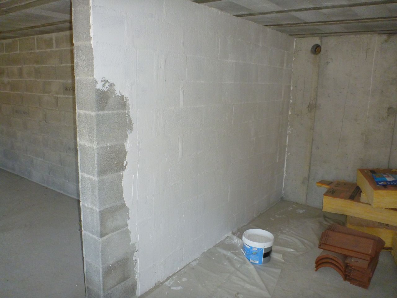 Une couche d'enduire afin de lisser les parpaings et avoir une certaine uniformité avec les murs en béton