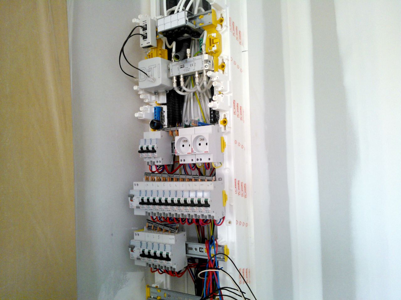 Le tableau électrique (équipé de deux prises de courant, utiles pour poser une futur alarme par exemple) avec en partie supérieure le mélangeur télé à 6 sorties, la prise test-téléphone et un répartiteur de prise RJ45 qui communique avec les différentes prises dans les pièces de vie.