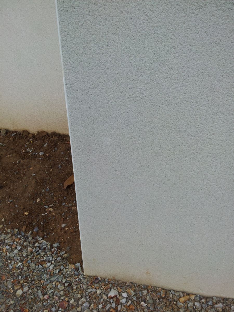 La reprise d\'un impact sur l\'enduit du garage. Cette retouche est un peu visible.