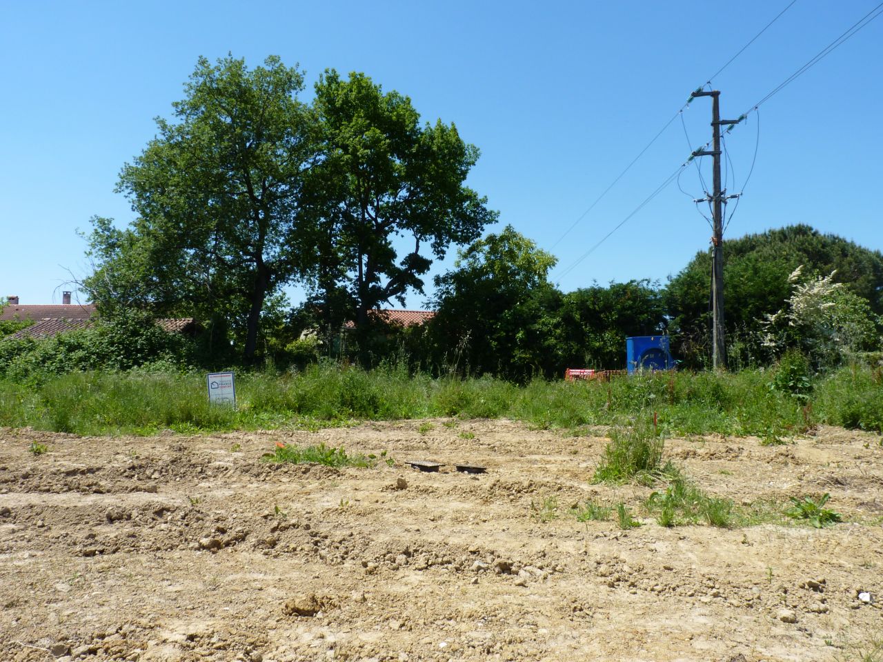 Sur cette photo,  gauche l ou sera ma maison (mon garage sera  peu prs au niveau du panneau). Le grand box EDF sera la limite sparative avec mon voisin du lot 17. La ligne lectrique juste au dessus sera enterre et la bande de terre sera une servitude EDF appartenant  mon voisin du 17.