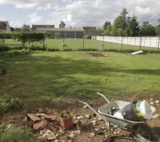 Gazon d'un mois (désherbé "à l'arrache"), décaissement pour terrasse au premier plan, potager à l'arrière plan et 3 cerisiers nains plantés du jour au bord du talus à gauche, et quelques moutons qui traînent ...