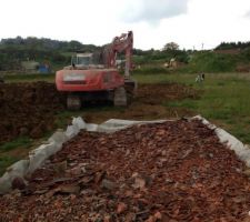 Arrivée de la pelle pour décaper la plateforme de la maison (40 cm de vegetale) puis mise à niveau (1m de denivelé entre le coté rue et le fond de la plateforme