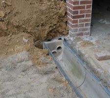 Pose du caniveau, avec arrivée du drain (tuyau haut), l'eau du caniveau sera évacuée en direction du puit de perte avec le second tuyau PVC (bas).