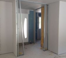 à gauche un bout de la cuisine, en face l'entrée vue de la salle à manger et à droite on voit la porte du bureau