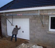 Les portes et les fenêtres sont posées. William teste la solidité de la porte de garage...