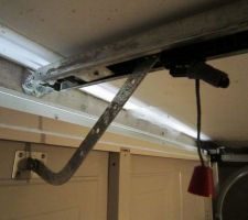 Motorisation de la porte du garage : patte de fixation sur la porte sectionnelle et du rail sur le linteau.