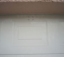 Motorisation de la porte du garage : patte de fixation sur la porte sectionnelle (vue de l'ext&eacute;rieur), avant une retouche peinture blanche sur les vis.