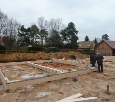 Pose des premiers éléments bois ceinturant la construction et reposant sur les pieux.