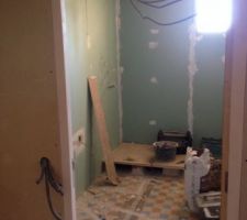 Salle de bain en plaque hydro, au sol les saign&eacute;es pour le passage du circuit d'eau, et le bac &agrave; douche pos&eacute;.