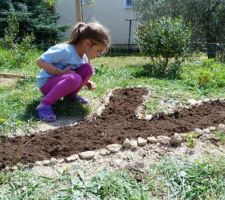 Un jardin pour les enfants : le futur massif de fleurs de ma fille dont le prénom commence par un "y" ;-). On a bien pioché la terre, puis elle a mis des cailloux autour pour faire jolie, on a semé un mélange de "pré fleuri", on a tassé, arrosé... reste plus qu'à attendre que ça pousse! Le massif du frère est en cours ;-)