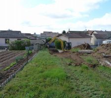 Le terrassier en train de démolir avec délicatesse le mur de soutènement mitoyen.