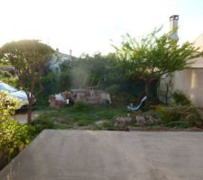 Le jardin vu de la cuisine avec la terrasse devant