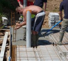 Un maçon tamponne le ferraillage pour s'assurer que le béton se tasse bien et que les bulles d'air succéptible de faire transiter l'humidité s?échappent du béton.