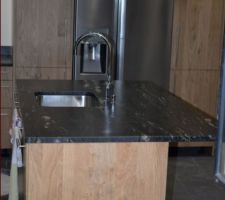 Ilot central, frigo entouré de deux armoires.