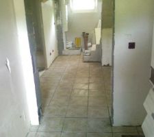 Pose du carrelage termin&eacute;e &agrave; la cave, en attente des joints. Vue de la buanderie sur le d&eacute;gagement du sous-sol.