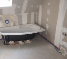 Baignoire asymétrique avec robinetterie encastré.