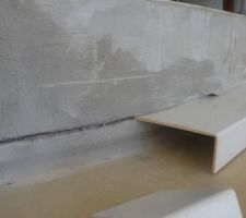 Il utilise des chutes d'équerres en plastique pour créer la réservation du joint de dilatation