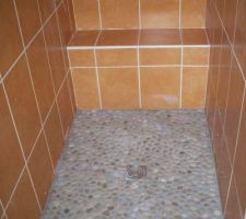 La douche à l'italienne terminée avec le banc rectifié et les galets achevés.