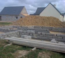 Après achevement des semelles en béton armé. Début des rangs de parpaings pour le vide sanitaire sous maison et garage.