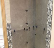 Pose du carrelage Concrete Fusé de la marque Aleluia Ceramica sur les murs de douche avec une mosaïque en pierre naturelle