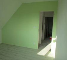 Chambre garçon. Mur vert pastel clair. Finitions avec plinthes en bois peintes. Sol en lame pvc imitation bois blanchi