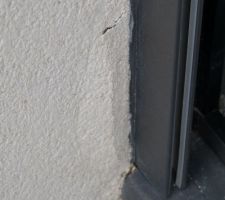 Décollement de l'enduit au pied d'une baie vitrée