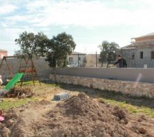 Mur de clôture enduit du côté intérieur avec jardinière en pierre pour les futurs arbustes de clôture.