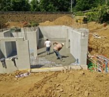 Épandage et lissage du béton coulé avec la benne et la grue.