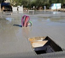 Dalle coulée avec un trou pour la trappe d'accès au vide sanitaire dans le garage