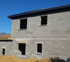 Vue de l'arrière de la maison, on voit le garage en charpente tradi à gauche et la partie surélevée en fermettes à droite. On commence à voir les débords de toiture en PVC Gris Anthracite.