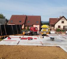 Ca y est nous arrivons à l'étape de la pose de la maison. La dalle est maintenant prête et bien sèches après quelques semaines de sèchage et l'équipe de BOOA prête à "assembler" la maison. A l'arrière plan à gauche les camions ont sur leurs remorques à chaque fois des pans de murs avec déjà pré fabriqué en usine en amont.